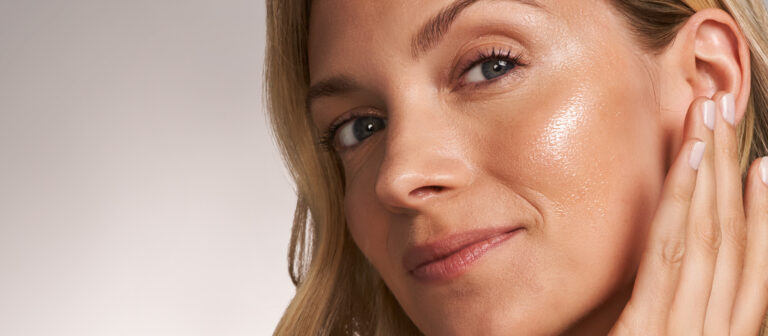 Kvinde med strålende hud efter at have brugt C-vitamin-serum.